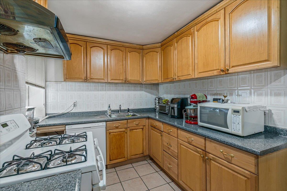 144-55 Melbourne Avenue, Unit 2E Queens, NY 11367 - Photo 16 of 21 a kitchen with stainless steel appliances granite countertop a sink a stove and cabinets