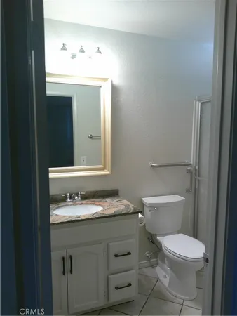 a bathroom with a granite countertop toilet sink and mirror