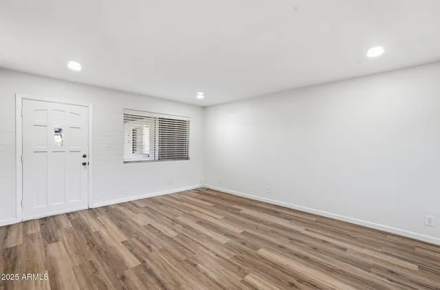 an empty room with wooden floor and windows