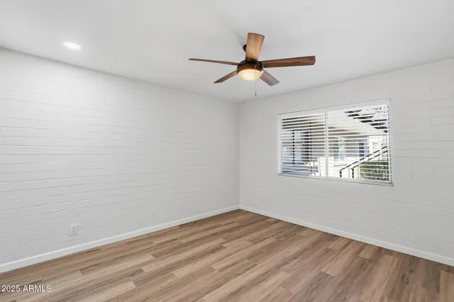 a view of empty room with wooden floor and fan
