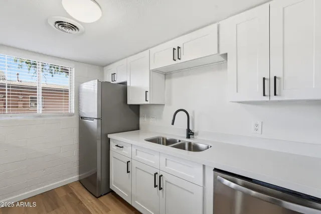 a kitchen with stainless steel appliances a sink cabinets and a window