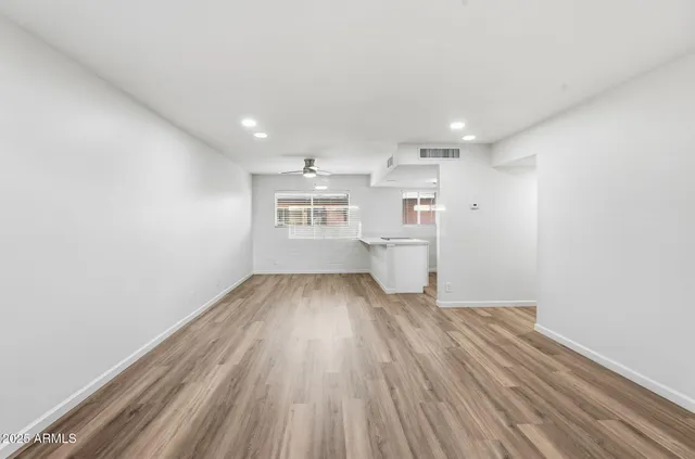 a view of kitchen and empty room with wooden floor