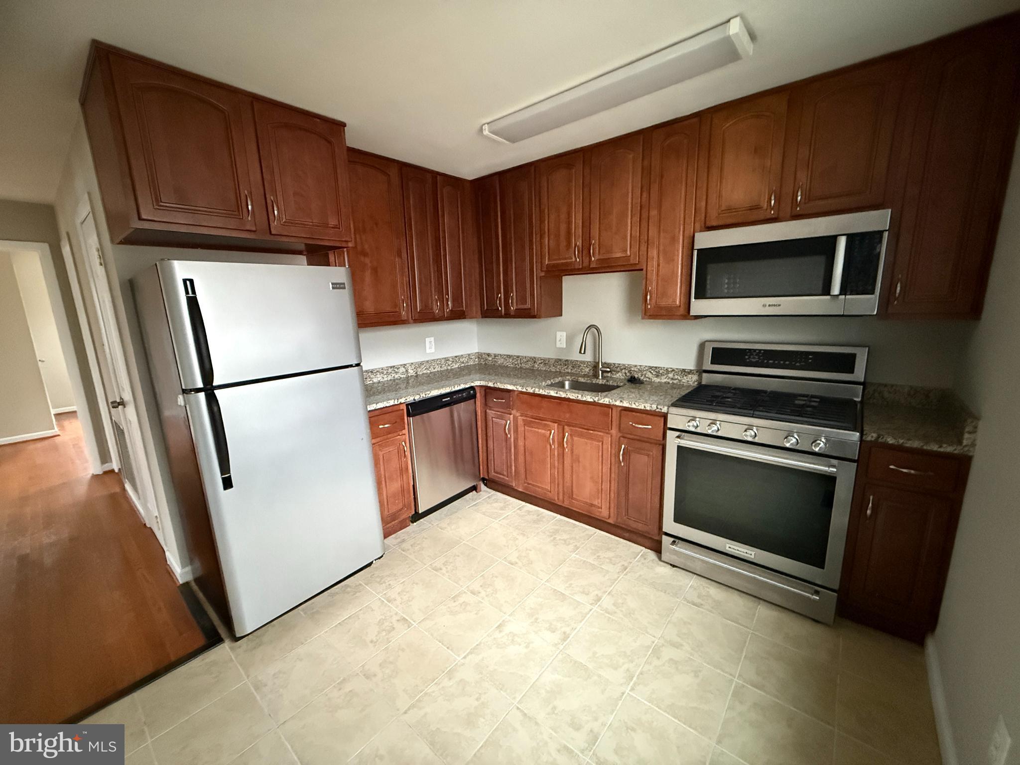 4542 Kingston Road Woodbridge, VA 22193 - Photo 6 of 15 a kitchen with stainless steel appliances granite countertop a refrigerator stove a sink dishwasher and microwave oven