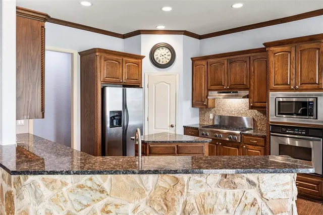 a kitchen with stainless steel appliances granite countertop a refrigerator a stove and a sink with wooden floor