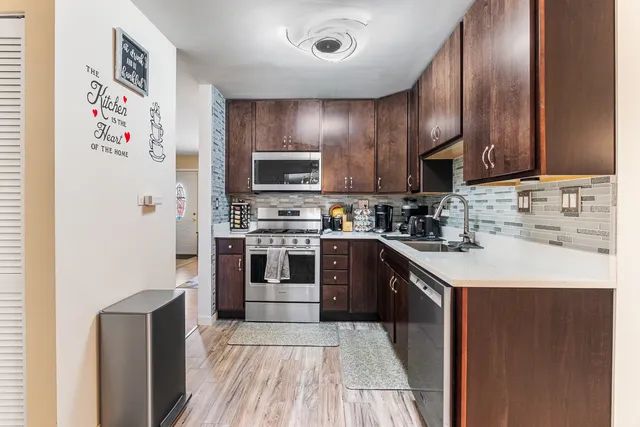 a kitchen with kitchen island granite countertop stainless steel appliances cabinets a sink and a counter top space