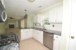 a kitchen with granite countertop a sink stove and cabinets