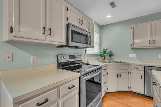 a kitchen with stainless steel appliances white cabinets and a stove top oven