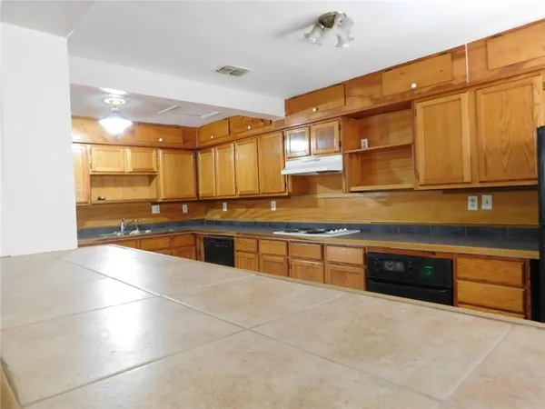 a large kitchen with stainless steel appliances a stove a sink and a microwave