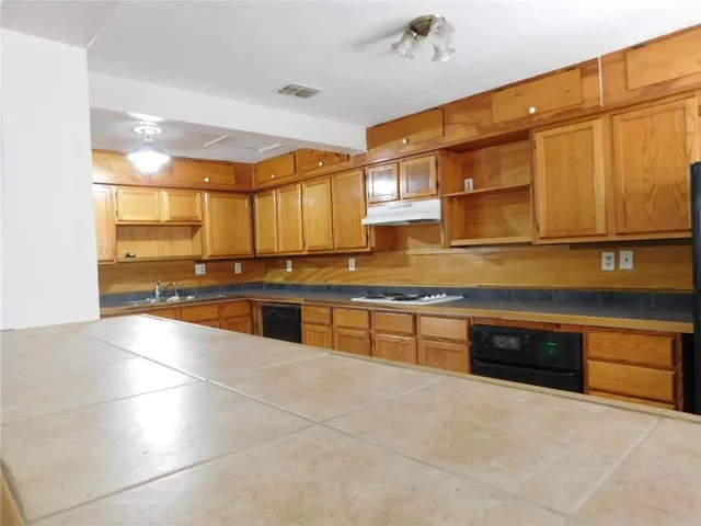 a large kitchen with stainless steel appliances a stove a sink and a microwave