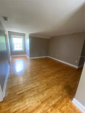 a view of empty room with wooden floor