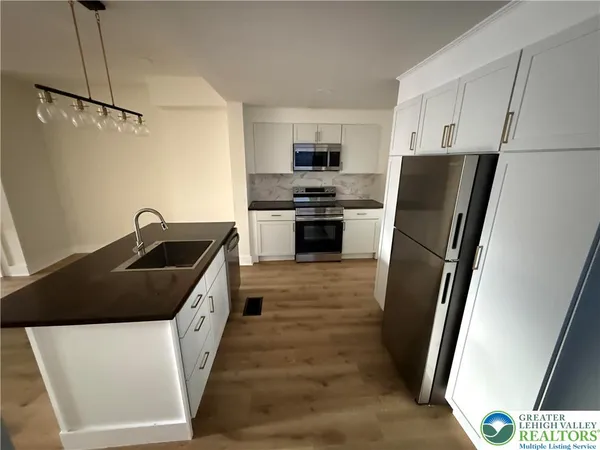 a kitchen with granite countertop a refrigerator and a sink