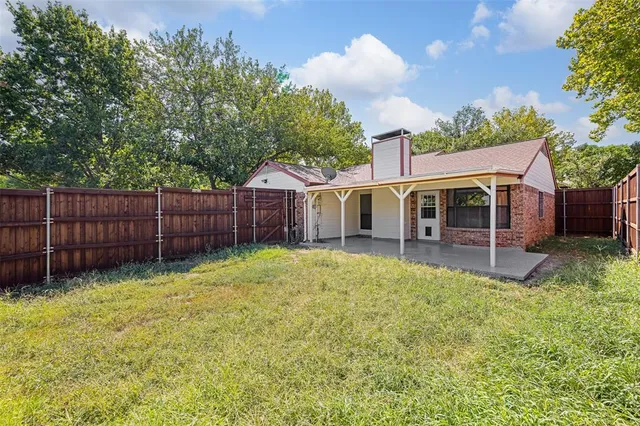 a view of a yard in front of a house with wooden fence
