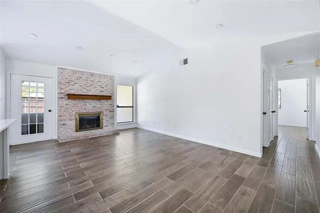 an empty room with wooden floor a fireplace and windows