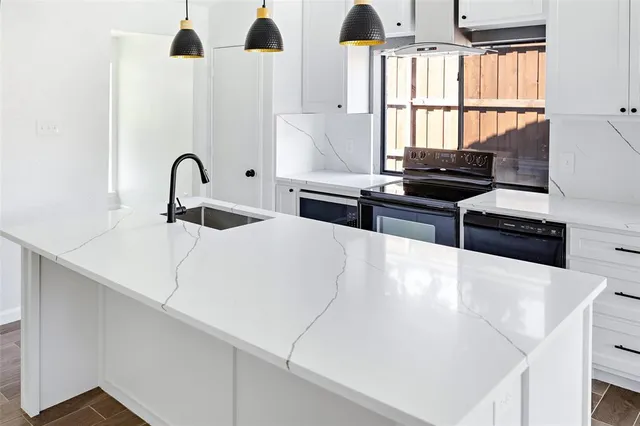 a kitchen with stainless steel appliances a stove a sink and a granite counter tops with white cabinets