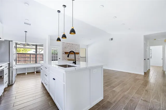 a kitchen with stainless steel appliances sink stove and wooden floor