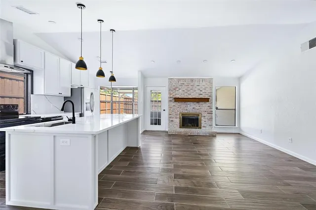 a view of a kitchen with wooden floor and a fireplace