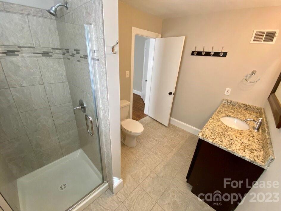 1708 Dilworth Road West, Unit 9 Charlotte, NC 28203 - Photo 8 of 14 a bathroom with a granite countertop shower and a toilet