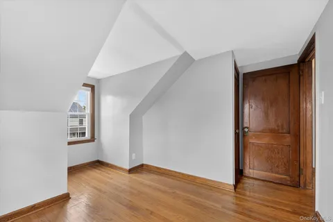 an empty room with wooden floor closet and windows