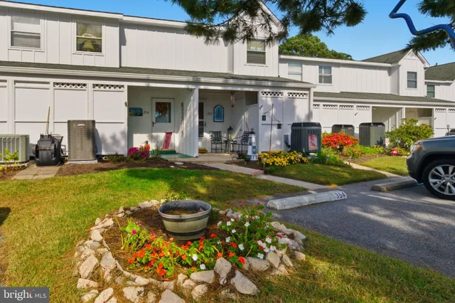 a view of a white house with swimming pool lawn chairs and a yard