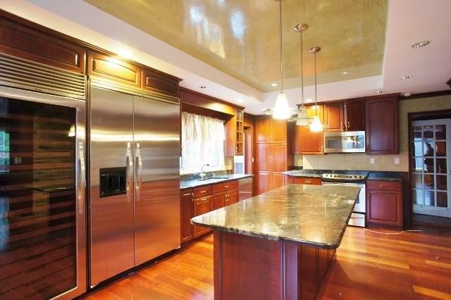 491 Den Road Stamford, CT 06903 - Photo 1 of 1 a kitchen with kitchen island a counter top space a sink a refrigerator and wooden floor