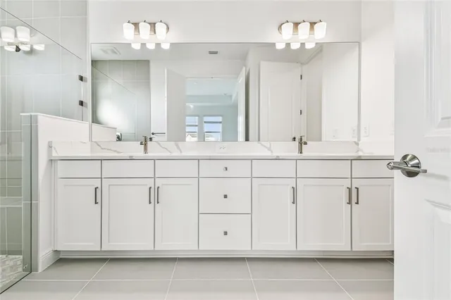 a spacious bathroom with a double vanity sink mirror and shower