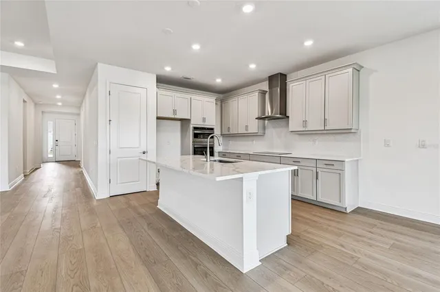 a large white kitchen with kitchen island a sink a stove a refrigerator and white cabinets with wooden floor