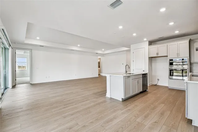 a view of a kitchen with a sink and dishwasher with wooden floor