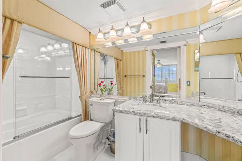 a bathroom with a granite countertop sink toilet a mirror and shower