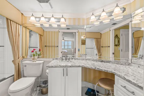 a bathroom with a granite countertop sink vanity mirror bathtub shower and toilet