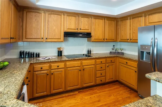 a kitchen with stainless steel appliances granite countertop a sink dishwasher stove and refrigerator with wooden floor