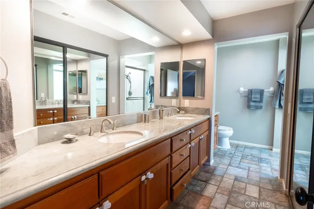 a bathroom with a granite countertop sink a toilet and a large mirror