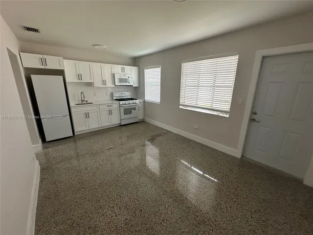 a view of a kitchen with refrigerator and windows