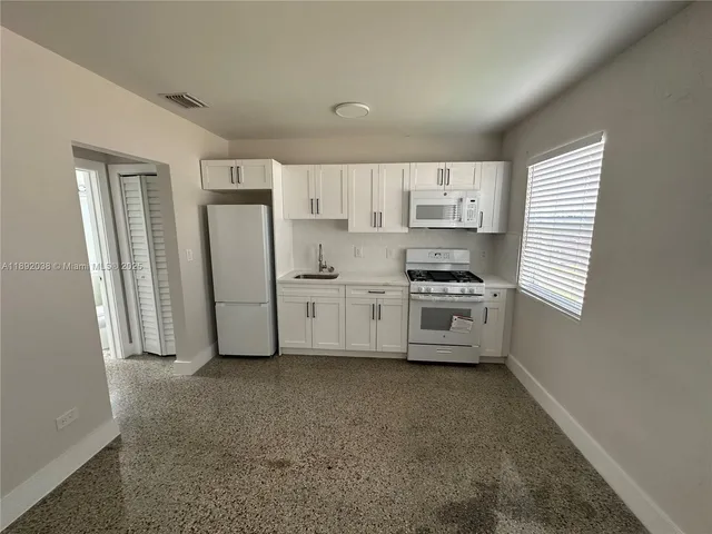 a kitchen with white cabinets and white appliances