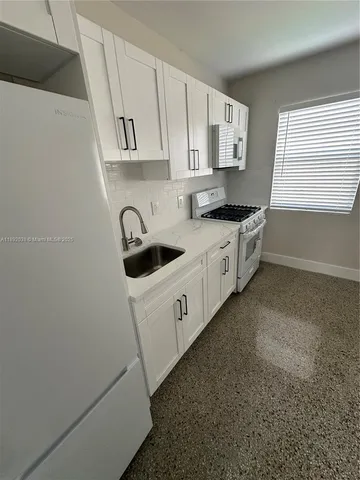 a kitchen with white cabinets white stainless steel appliances and sink