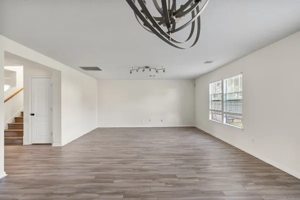 a view of an empty room with wooden floor and window