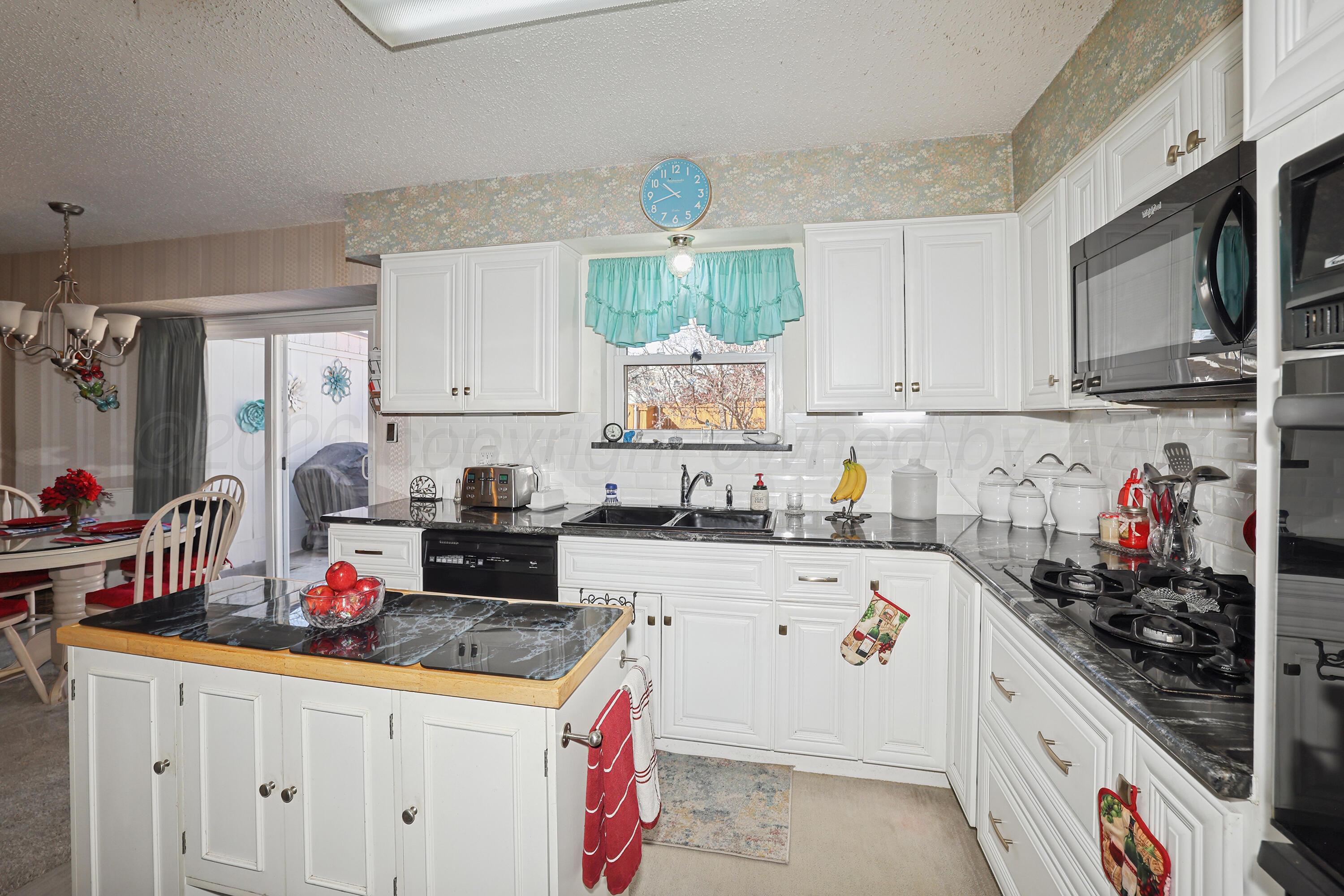 3708 Wayne Street Amarillo, TX 79109 - Photo 15 of 36 a kitchen with kitchen island granite countertop a sink dishwasher stove and white cabinets