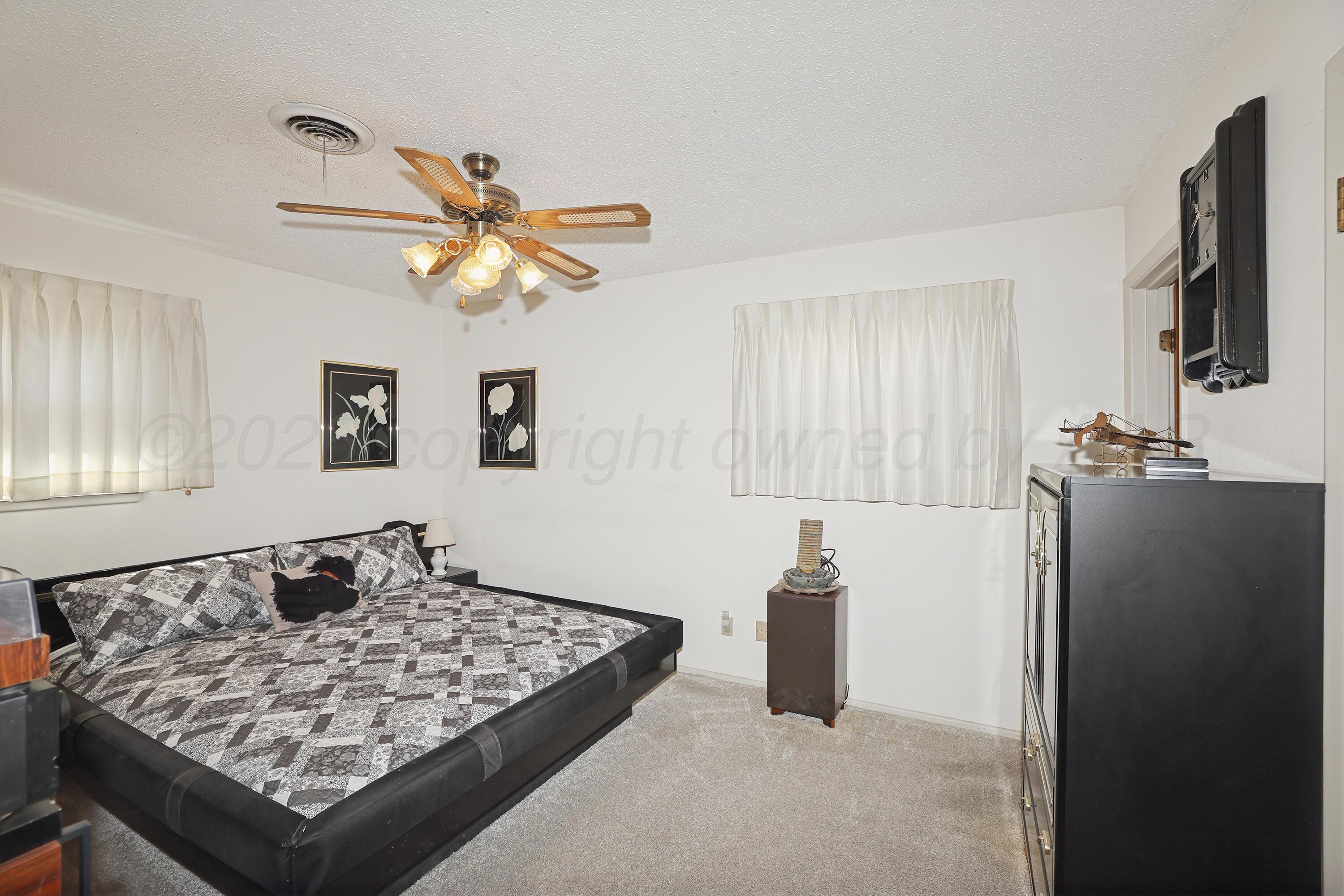 3708 Wayne Street Amarillo, TX 79109 - Photo 16 of 36 a bedroom with a bed and a chandelier
