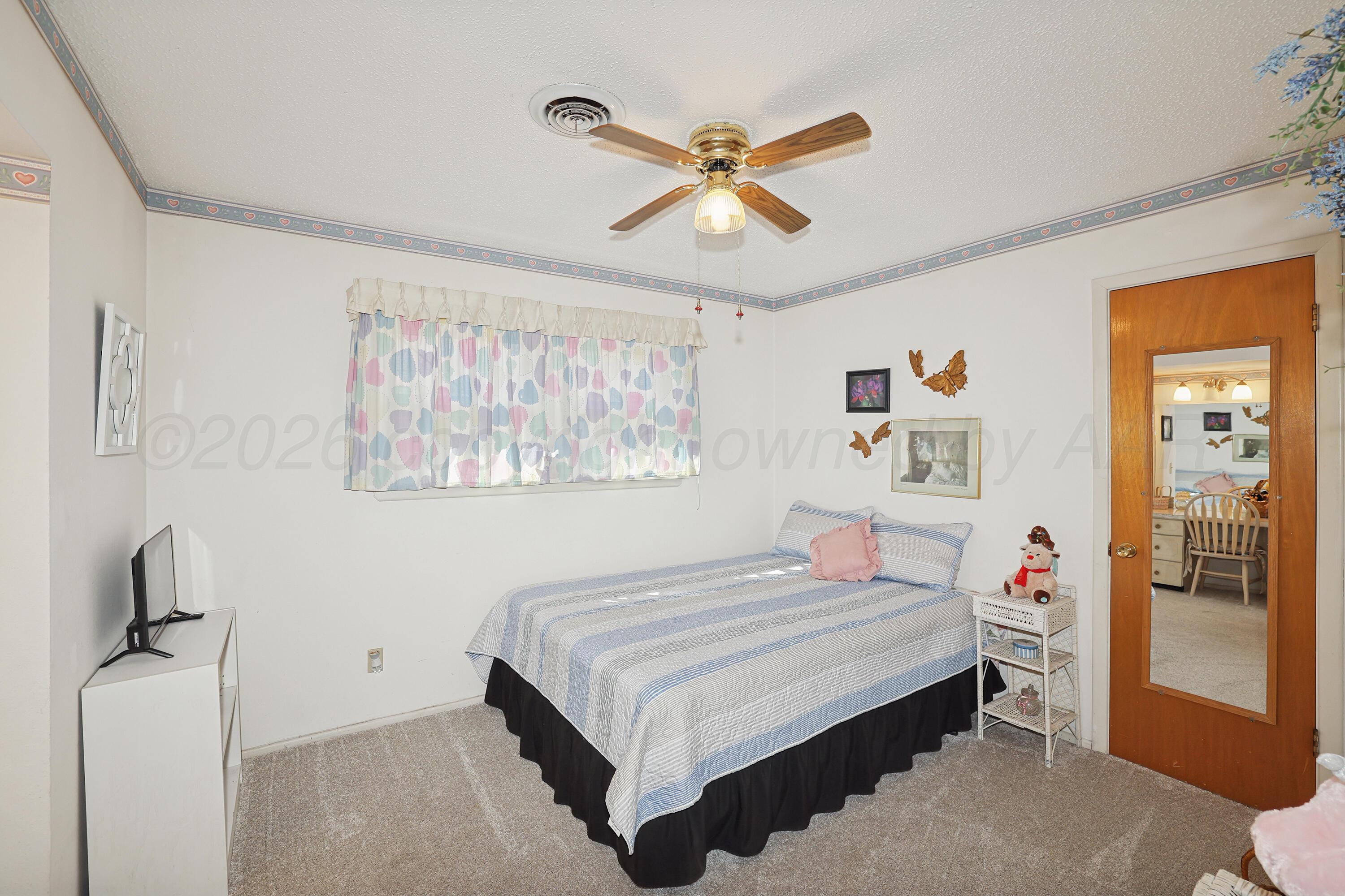 3708 Wayne Street Amarillo, TX 79109 - Photo 20 of 36 a bedroom with a bed and a chandelier