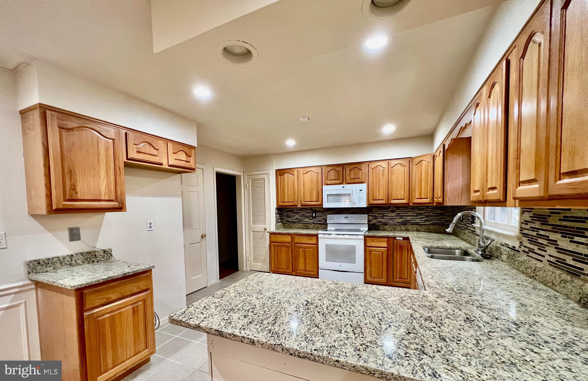 7510 Sanner Road Laurel, MD 20723 - Photo 4 of 26 a kitchen with stainless steel appliances granite countertop a stove top oven a sink and a refrigerator