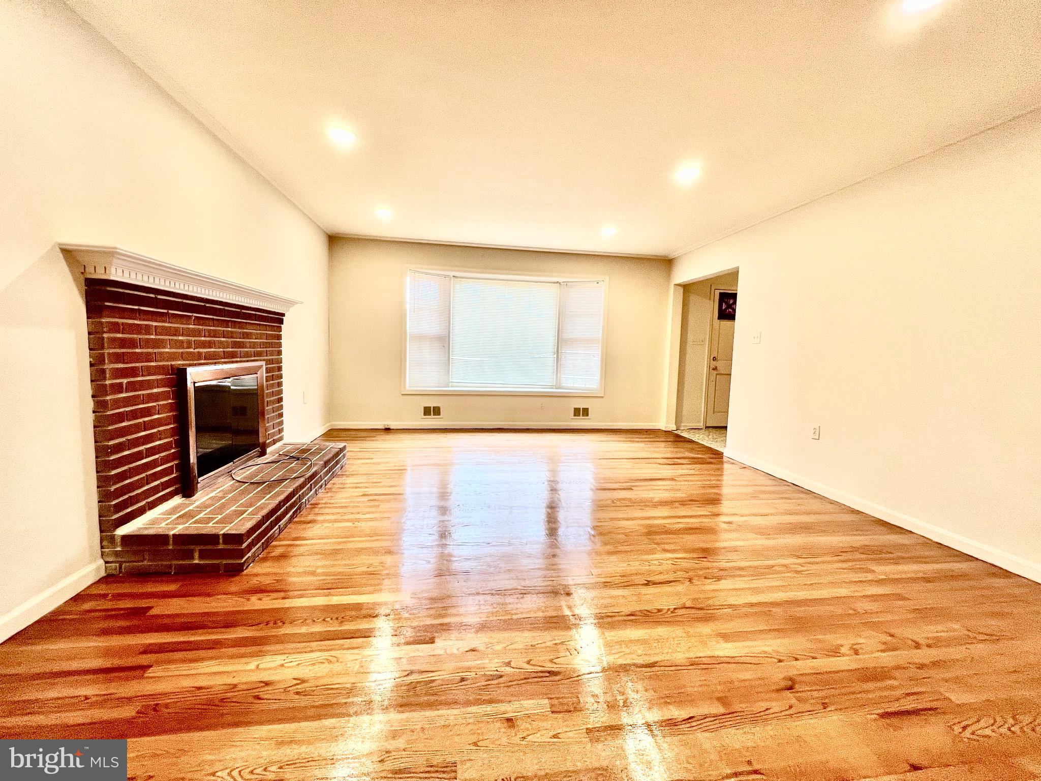 7510 Sanner Road Laurel, MD 20723 - Photo 7 of 26 a view of empty room with wooden floor and fireplace