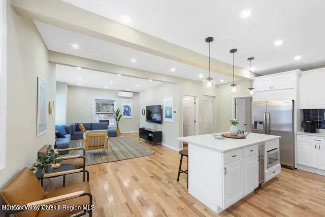 a large white kitchen with a stove a sink dishwasher and a refrigerator with wooden floor