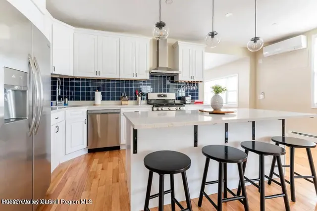 a kitchen with stainless steel appliances a table chairs refrigerator and cabinets