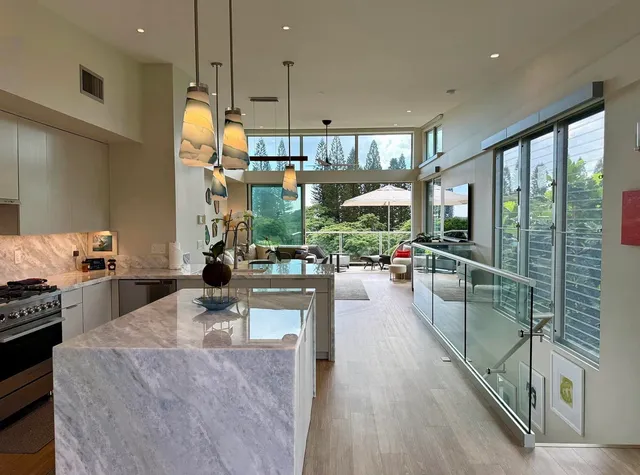 a living room with stainless steel appliances kitchen island granite countertop a large window and a counter space