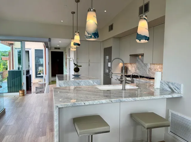 a kitchen with kitchen island granite countertop a sink cabinets and wooden floor