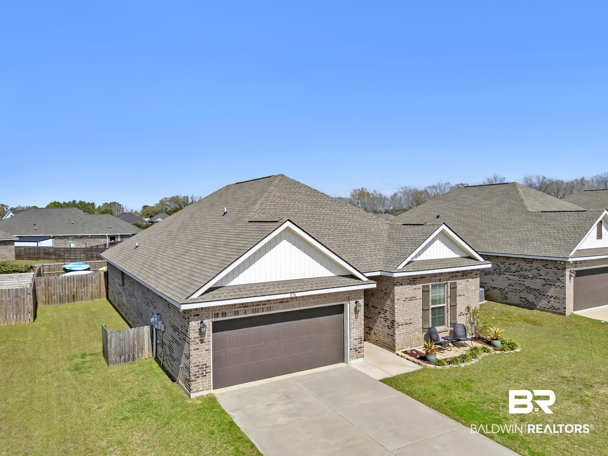 1176 Stella Road Foley, AL 36535 - Photo 2 of 40 View of front facade featuring a shingled roof, brick siding, concrete driveway, and an attached garage
