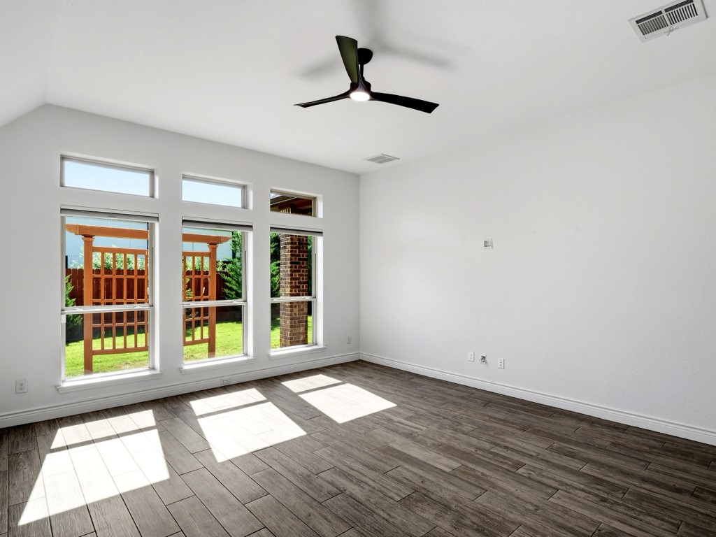 109 Lake Spring Circle Georgetown, TX 78633 - Photo 27 of 38 The second bedroom experiences natural light flooding through a wall of windows with transoms with wood-look tile flooring and a refreshing ceiling fan.