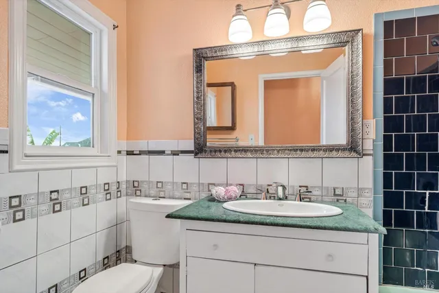 a bathroom with a granite countertop sink a toilet and a mirror