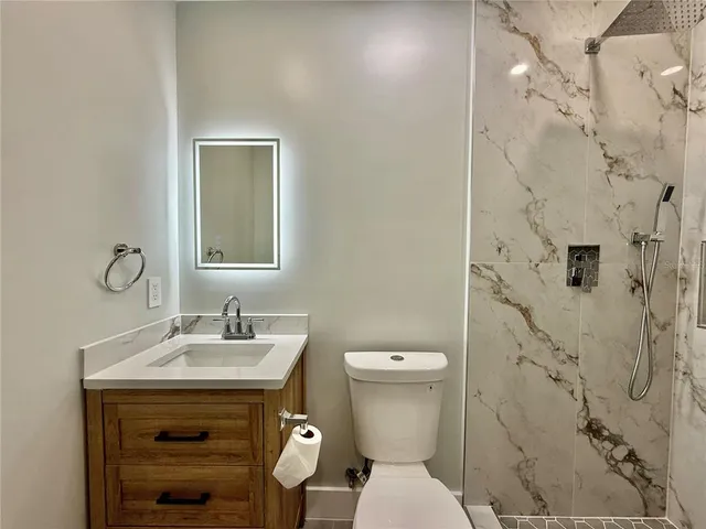 a bathroom with a granite countertop sink toilet and shower