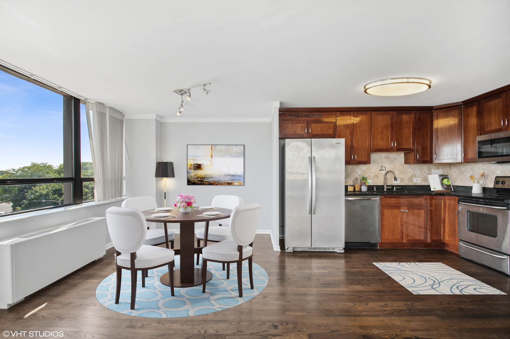 5701 North Sheridan Road, Unit 5T Chicago, IL 60660 - Photo 10 of 27 a kitchen with stainless steel appliances granite countertop a stove a refrigerator a kitchen island with chairs and wooden floor