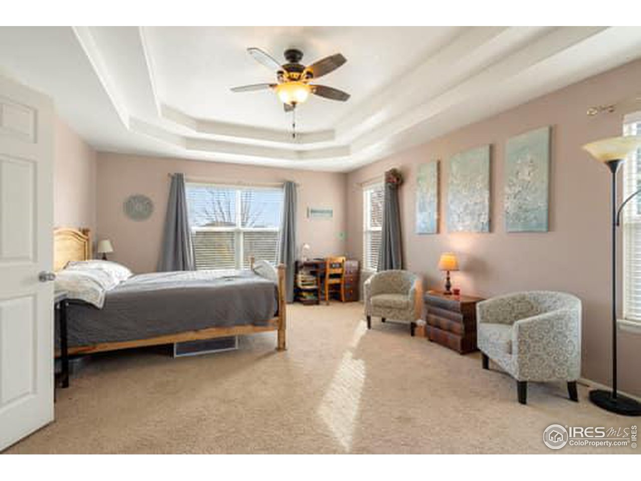 1545 Edenbridge Drive Windsor, CO 80550 - Photo 12 of 28 a spacious bedroom with a bed a couch and a chandelier